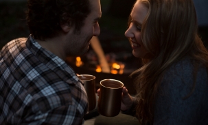 couple sharing hot chocolate at camping engagement